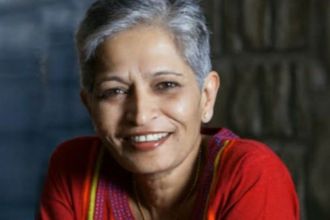 Gauri lankesh is wearing a red top with colorful embroidery, set against a blurred, dark background. The vibrancy of the attire contrasts the somber discussions on right-wing extremism in India.